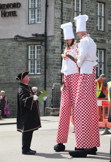 Town Crier looking up to stilt people